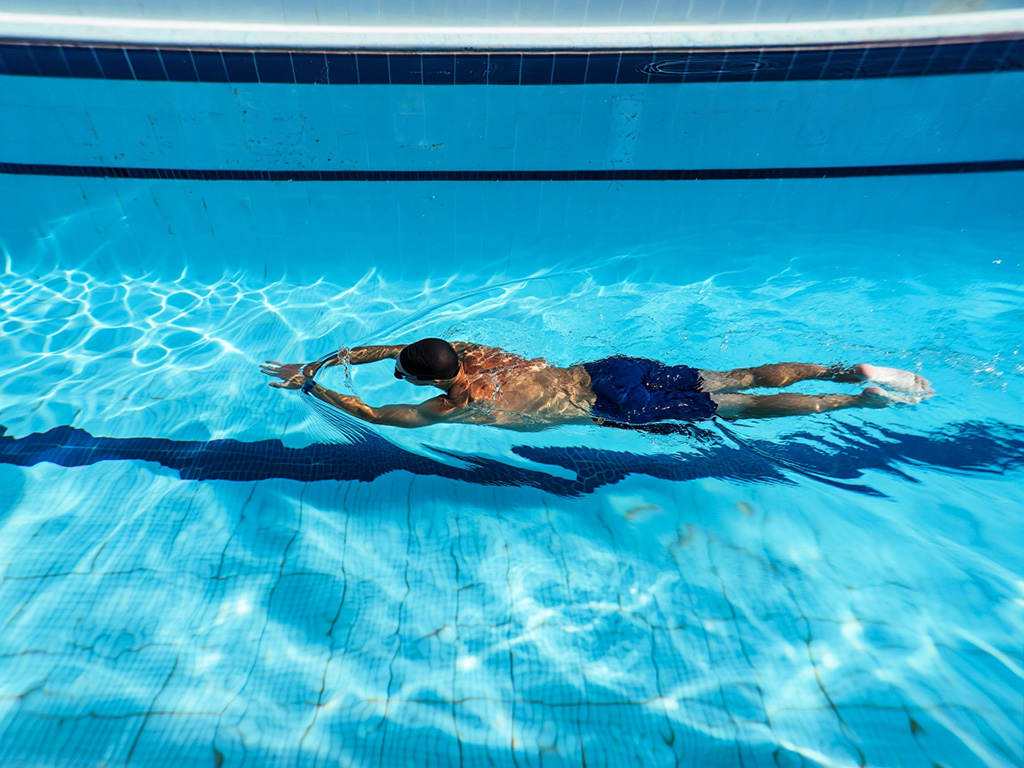 Person som simmar i en lugn pool med blått vatten